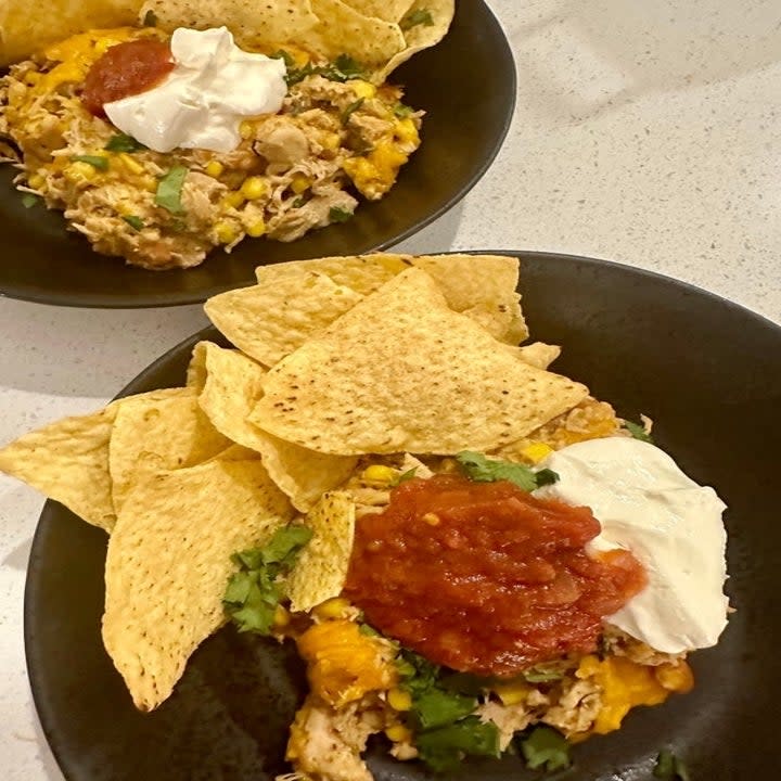 chicken taco casserole in a bowl with salsa, sour cream, and chips