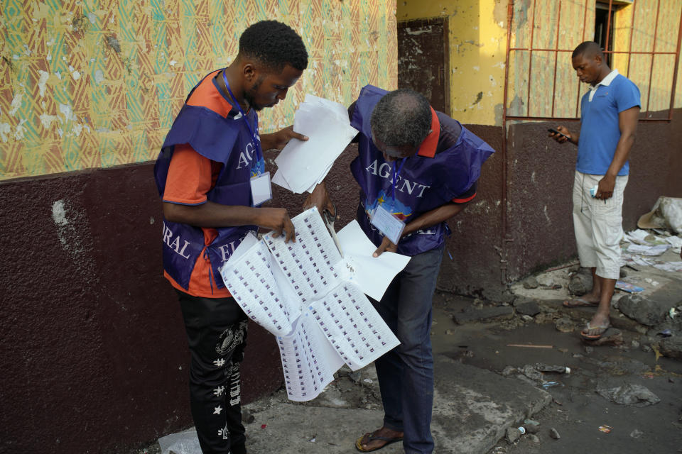 Election officials check the voter's registrations lists just brought in at the Les Anges primary school, just before the vote is scheduled to close, in Kinshasa, Congo. Sunday Dec. 30, 2018. The voting process was delayed when angry voters burned six voting machines and ballots mid-day, angered by the fact that the registrations lists had not arrived. Replacement machines had to be brought in, and voting started at nightfall, 12 hours late. Forty million voters are registered for a presidential race plagued by years of delay and persistent rumors of lack of preparation. (AP Photo/Jerome Delay)