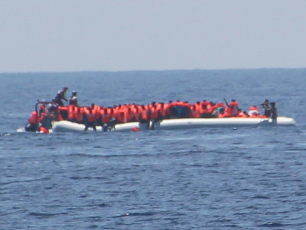 The crew of Moas' Iuventa rescue ship photographed what appeared to be a Libyan coastguard officer pointing a weapon at refugees (far right): Moas