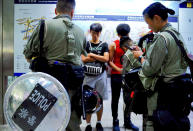 Riot police check passengers' bags at airport express central station in downtown Hong Kong, Saturday, Sept. 7, 2019. Hong Kong authorities were limiting airport transport services and controlling access to terminals Saturday as they braced for a second weekend of disruption following overnight demonstrations that turned violent. (AP Photo/Vincent Yu)