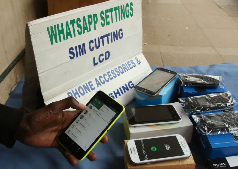 A street vendor adjusts the internet settings on a customer's mobile phone in Harare