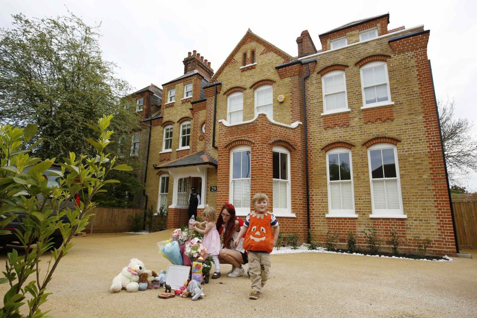 A mother and children place flowers outside a house where the bodies of three children were found, in New Malden, southwest London