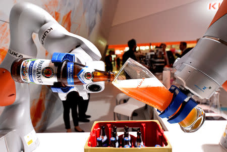 FILE PHOTO: A robotic arm fills a glass with Bavarian Weiss beer at the booth of German company Kuka at the world's biggest industrial fair, "Hannover Fair", in Hanover, Germany April 24, 2017. REUTERS/Fabian Bimmer/File Photo