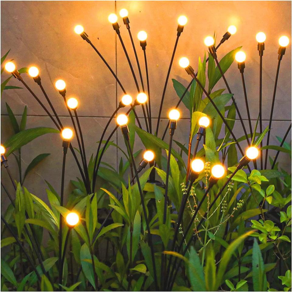 Small stake lights shaped like blades of grass among garden plants