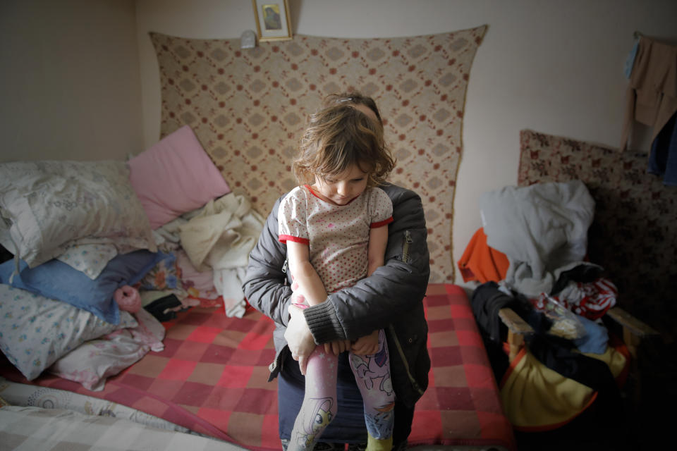 A little girl sits in her mother's arms in Nucsoara, Romania, Saturday, Jan. 9, 2021. Valeriu Nicolae and his team visited villages at the foot of the Carpathian mountains, northwest of Bucharest, to deliver aid. The rights activist has earned praise for his tireless campaign to change for the better the lives of the Balkan country’s poorest and underprivileged residents, particularly the children. (AP Photo/Vadim Ghirda)