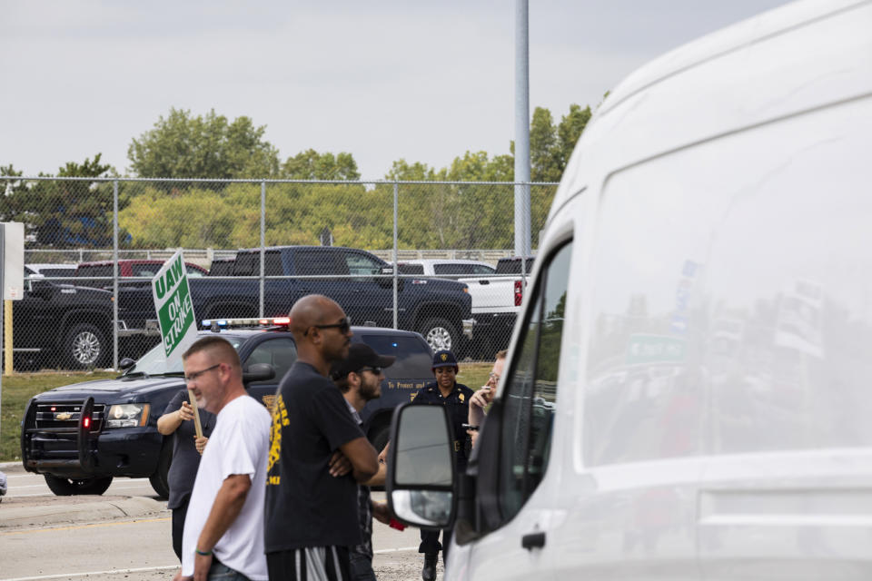 A City of Flint police officer approaches union members preventing cars from entering the General Motors Flint Assembly Plant as United Automobile Workers remain on strike against GM on Tuesday, Sept. 17, 2019, in Flint, Mich. GM and the union are negotiating at a time of troubling uncertainty for the U.S. auto industry. (Sara Faraj/MLive.com/The Flint Journal via AP)