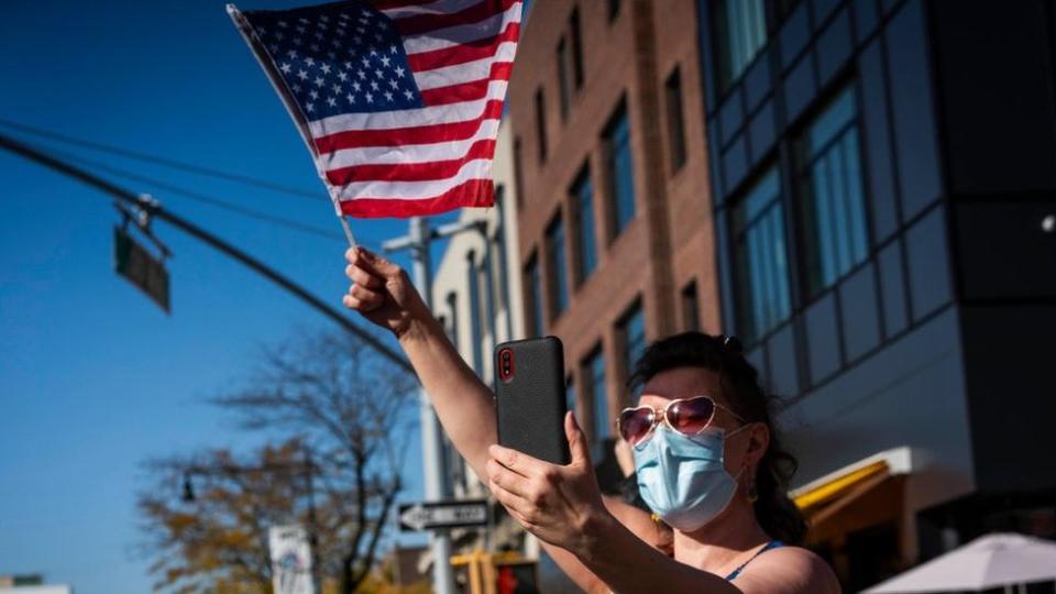 A woman waves an American flag during a celebration in Astoria