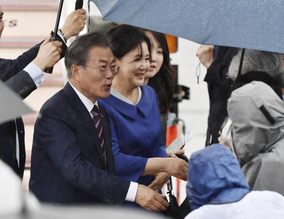 South Korean President Moon Jae-in, left, and his wife Kim Jung-sook are greeted on their arrival at Kansai International Airport in Izumisano, Osaka prefecture, western Japan, Thursday, June 27, 2019. Group of 20 leaders gather in Osaka on June 28 and 29 for their annual summit.(Nobuki Ito/Kyodo News via AP)