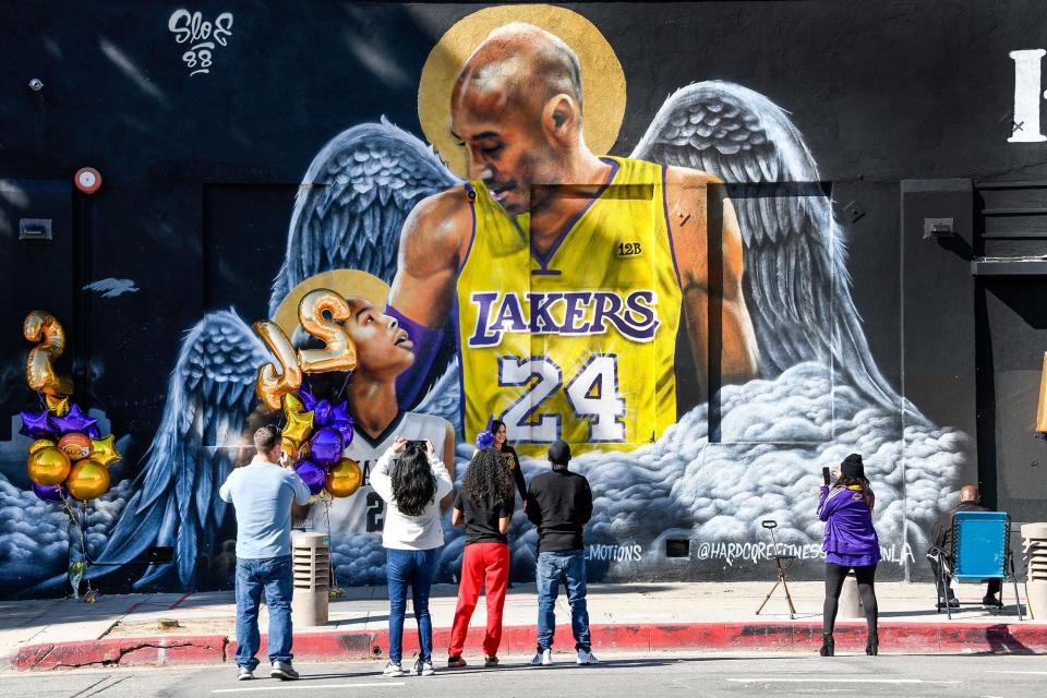 Fans gather at a mural of Kobe Bryant and his daughter Gianna painted on the wall of Hardcore Fitness Bootcamp gym in downtown Los Angeles on Jan 26, 2021. Bryant, his daughter and 7 others died in a helicopter crash in Calabasas, Calif. on Jan. 26, 2020. 