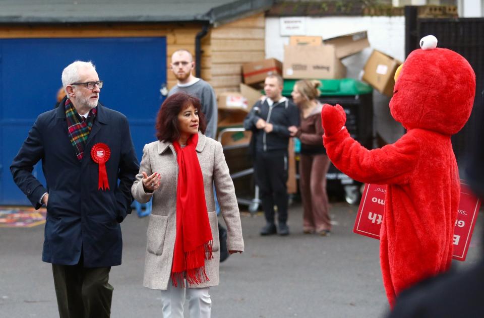 Labour Party leader Jeremy Corbyn and his wife Laura Alvarez look on as a person in a costume of Sesame Street character Elmo waves (REUTERS)