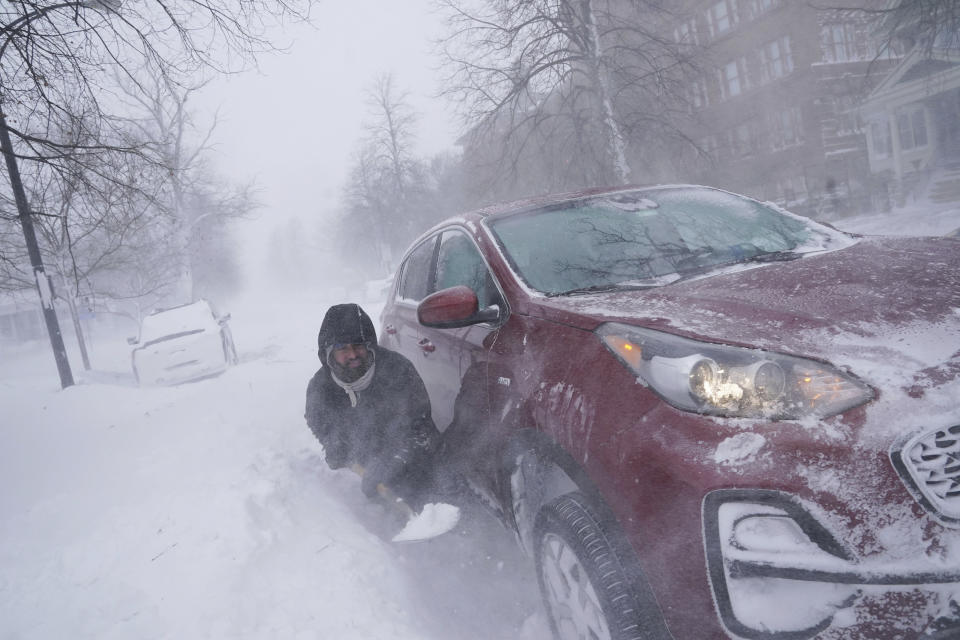 Gamaliel Vega tries to dig out his car on Lafayette Avenue after he got stuck in a snowdrift about a block from home while trying to help rescue his cousin, who had lost power and heat with a baby at home across town during a blizzard in Buffalo, N.Y., on Saturday, Dec. 24, 2022. (Derek Gee/The Buffalo News via AP)