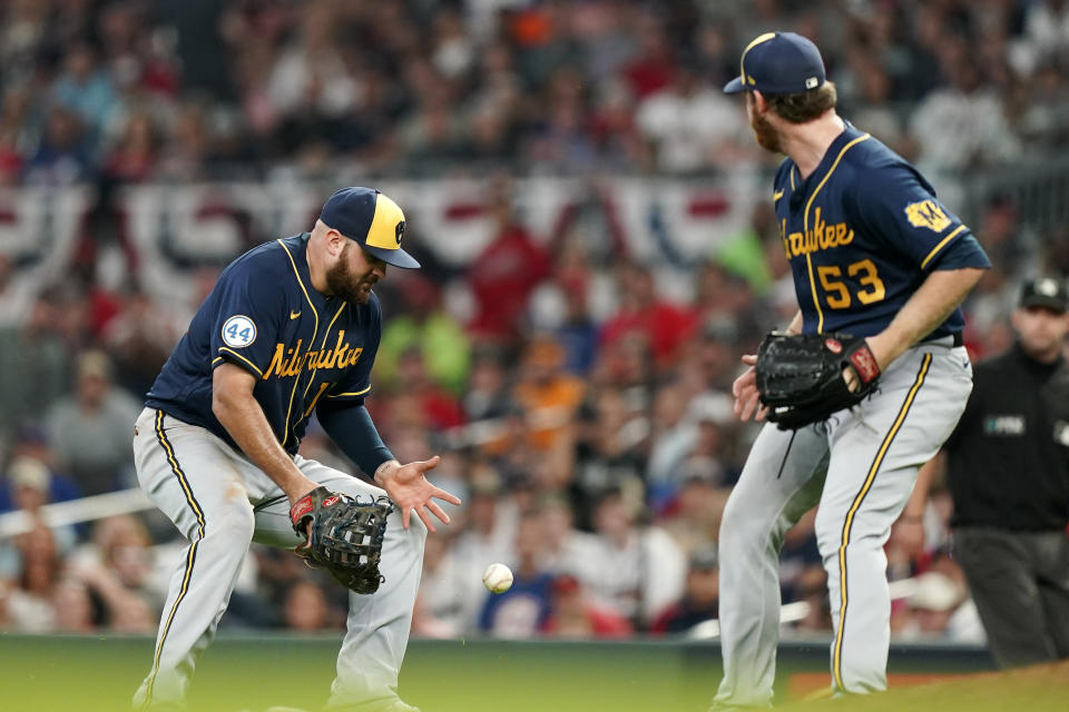 The ball drops between Milwaukee Brewers first baseman Rowdy Tellez (11) and Milwaukee Brewers starting pitcher Brandon Woodruff (53) during the seventh inning of Game 4 of a baseball National League Division Series against the Atlanta Braves, Tuesday, Oct. 12, 2021, in Atlanta. (AP Photo/Brynn Anderson)