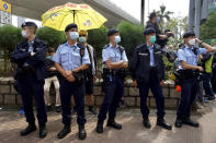 Police officers stand guard as supporters queue up outside a court to try get in for a hearing in Hong Kong Monday, March 1, 2021. People gathered outside the court Monday to show support for 47 activists who were detained over the weekend under a new national security law that was imposed on the city by Beijing last year. (AP Photo/Vincent Yu)