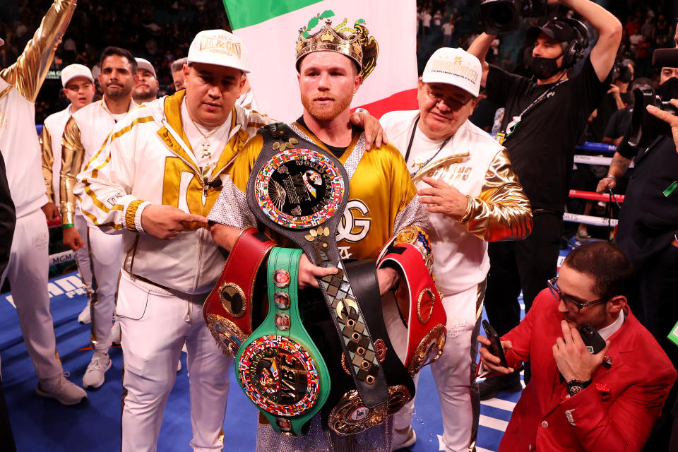 Canelo Alvarez (pictured middle) wears a crown and poses with the belts after his championship bout with Caleb Plant. 