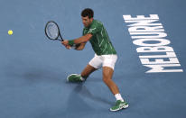 Serbia's Novak Djokovic makes a backhand return to Canada's Milos Raonic during their quarterfinal match at the Australian Open tennis championship in Melbourne, Australia, Tuesday, Jan. 28, 2020. (AP Photo/Dita Alangkara)