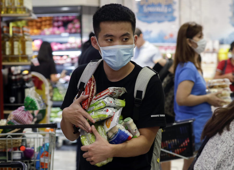 A man wearing a protective mask looks for the start of the queue at a grocery store in Taguig, metropolitan Manila, Philippines on Friday, March 13, 2020. Many people trooped to supermarkets and stocked up on supplies as the Philippine president announced Thursday that domestic travel to and from metropolitan Manila will be suspended for a month and authorized sweeping quarantines in the crowded capital to fight the new coronavirus.(AP Photo/Aaron Favila)
