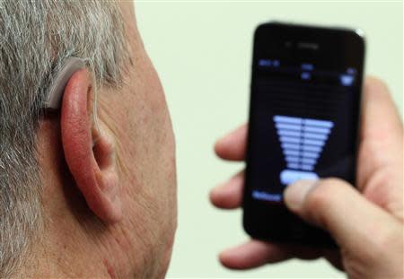 An employee of GN, the world's fourth largest maker of hearing aids, demonstrates the use of ReSound LiNX in Vienna November 22, 2013. REUTERS/Heinz-Peter Bader