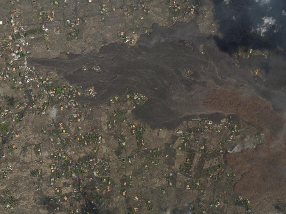 In this Saturday, Sept. 25, 2021 satellite photo from Planet Labs Inc. lava and ash from a volcano on the Canary island of La Palma, Spain can be seen. A Spanish island volcano that has buried more than 500 buildings and displaced over 6,000 people since last week lessened its activity on Monday, although scientists warned that it was too early to declare the eruption phase finished and authorities ordered residents to stay indoors to avoid the unhealthy fumes from lava meeting sea waters. (Planet Labs Inc. via AP)