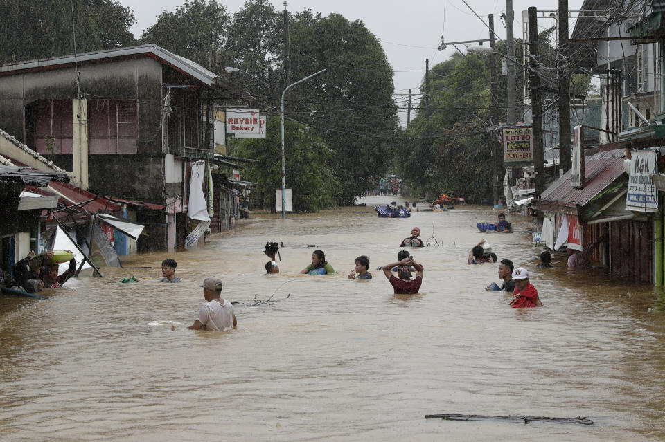 Residents negotiate a flooded road as floods continue to rise in Marikina, Philippines due to Typhoon Vamco on Thursday, Nov. 12, 2020. The typhoon swelled rivers and flooded low-lying areas as it passed over the storm-battered northeast Philippines, where rescuers were deployed early Thursday to help people flee the rising waters. (AP Photo/Aaron Favila)