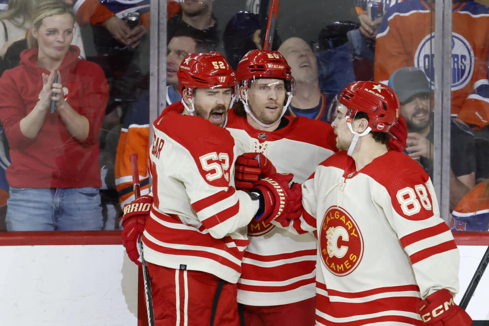 Calgary Flames' MacKenzie Weegar, left, celebrates with Blake Coleman and Andrew Mangiapane after scoring against the Edmonton Oilers during the second period of an NHL hockey game Saturday, Jan. 20, 2024, in Calgary, Alberta. (Larry MacDougal/The Canadian Press via AP)