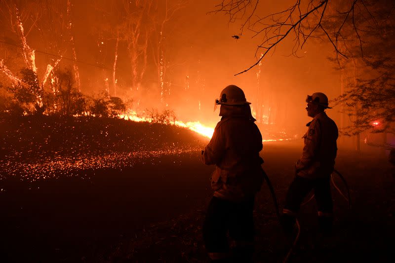 Los equipos del Servicio Rural de Bomberos de Nueva Gales del Sur protegen las propiedades de Waratah Road y Kelyknack Road cuando el incendio de Three Mile se aproxima a Mangrove Mountain, Australia