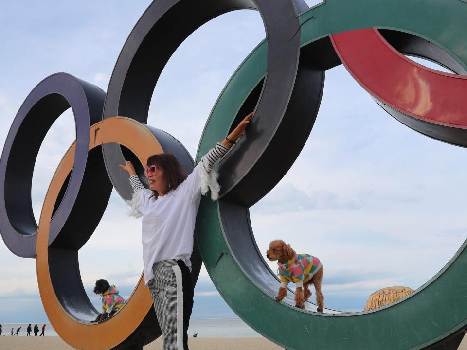 A woman poses with her dogs next to Olympic Rings in South Korea.
