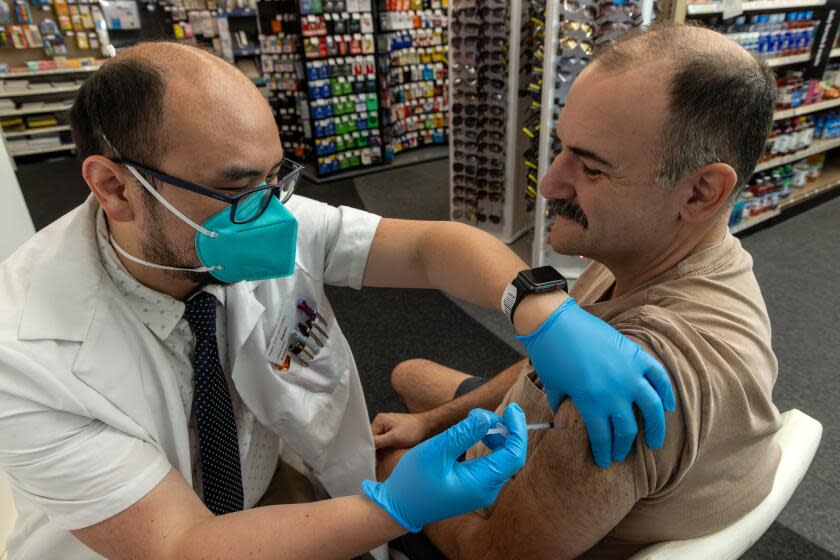 EAGLE ROCK, CA - SEPTEMBER 14: Pharmacist Aaron Sun administers new vaccine COMIRNATY® (COVID-19 Vaccine, mRNA) by Pfizer, to Jimmy Smagula at CVS Pharmacy in Eagle Rock, CA. (Irfan Khan / Los Angeles Times)