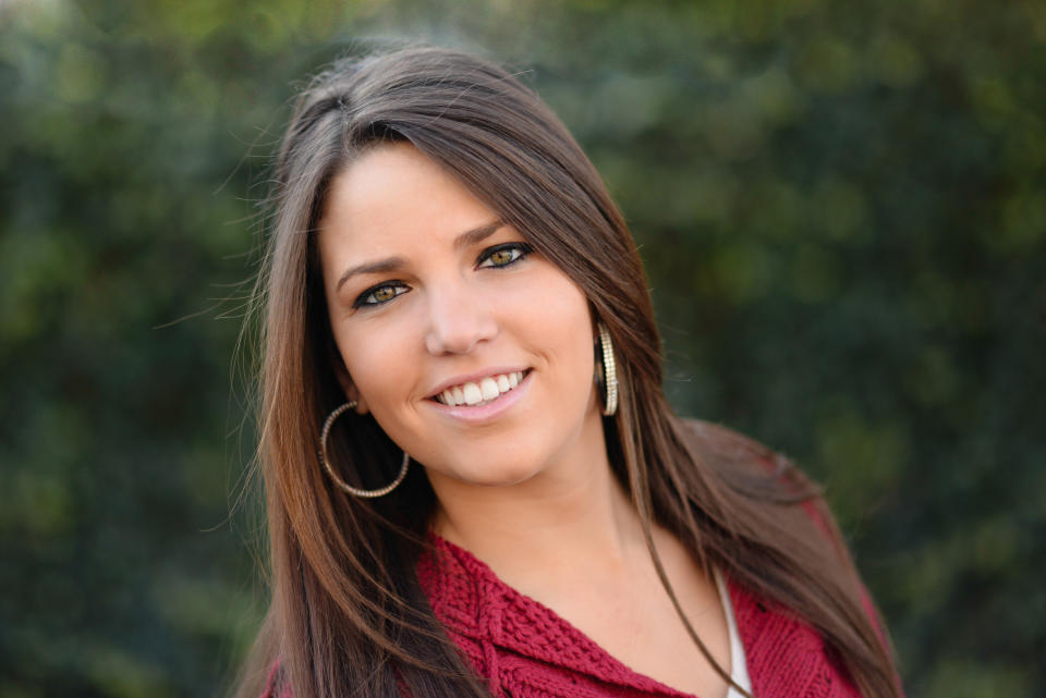 Woman smiling outdoors wearing hoop earrings and a knit top