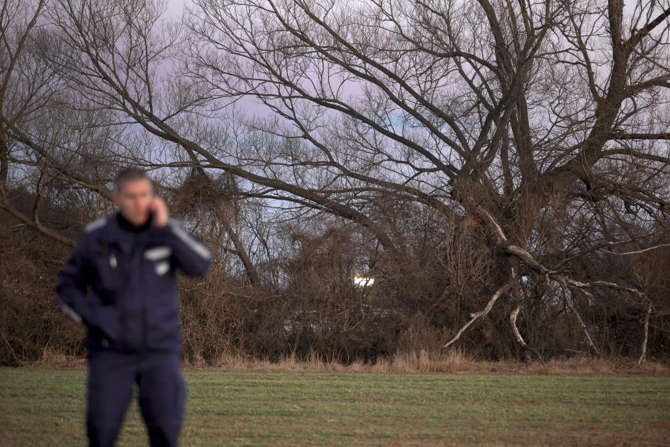 A police officer stands guard at the site where an abandoned truck was found, containing the bodies of 18 migrants who appeared to have suffocated to death inside a secret compartment under a load of lumber, in the village of Lokorsko, near Sofia, Bulgaria, Friday, Feb. 17, 2023. The Interior Ministry said that according to initial information, the truck was carrying about 40 migrants and the survivors were taken to nearby hospitals for emergency treatment. (AP Photo/ Valentina Petrova)