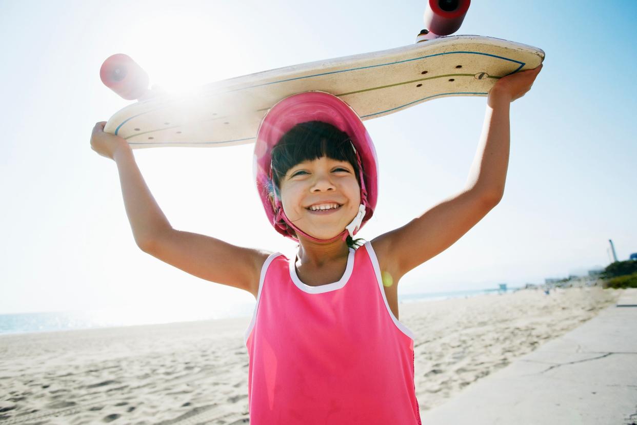 Mixed race girl holding skateboard at beach