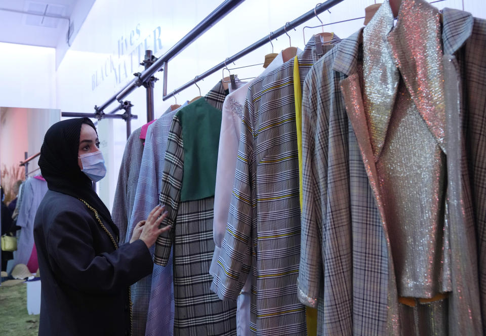 Fashion designer Zineb Hazim, from Morocco, touches her creations, part of the Black Lives Matter Spring Summer 2022 collective fashion event, unveiled during the Milan Fashion Week, in Milan, Italy, Tuesday, Sept. 21, 2021. (AP Photo/Antonio Calanni)