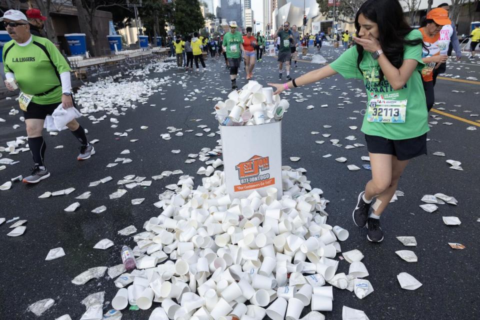 Plastic cups spill out of a trash bin and all over the street.