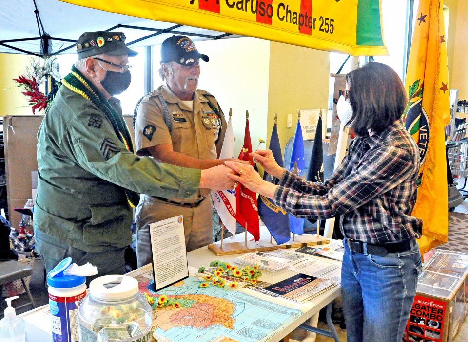 Dennis Amily and Jeff Sampsel, members of the Vietnam Veterans of America Barry Caruso Chapter in Wooster hand a poppy to Joyce Vura at Buehler's MIlltown.