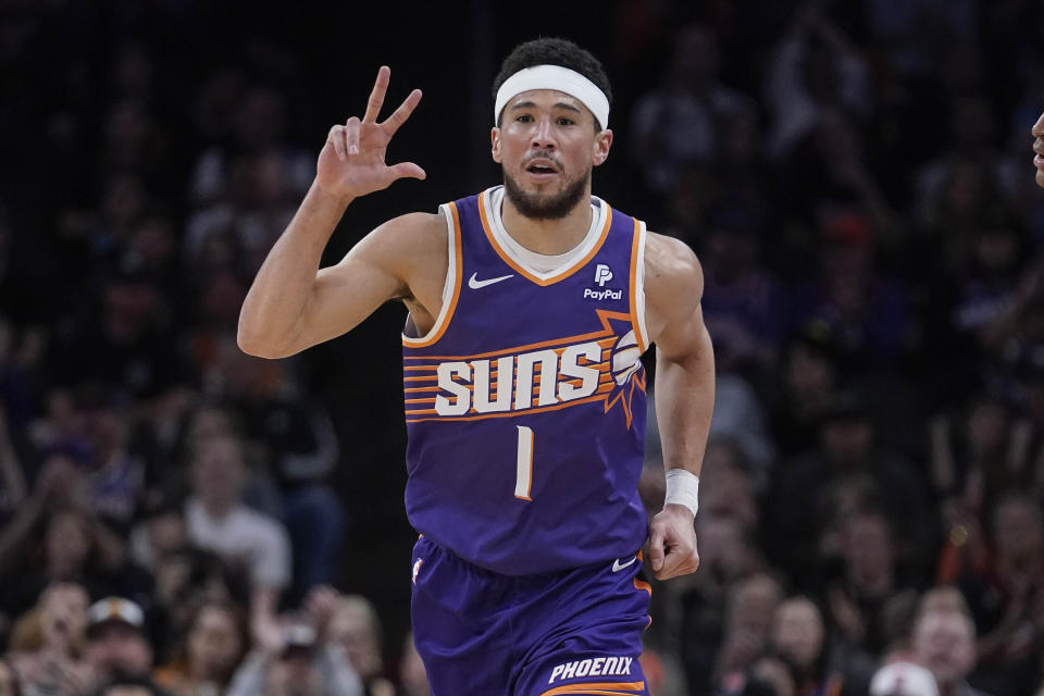 Phoenix Suns guard Devin Booker (1) gestures after hitting a 3-point basket against the Houston Rockets during the first half of an NBA basketball game in Phoenix, Saturday, March. 2, 2024. (AP Photo/Darryl Webb)