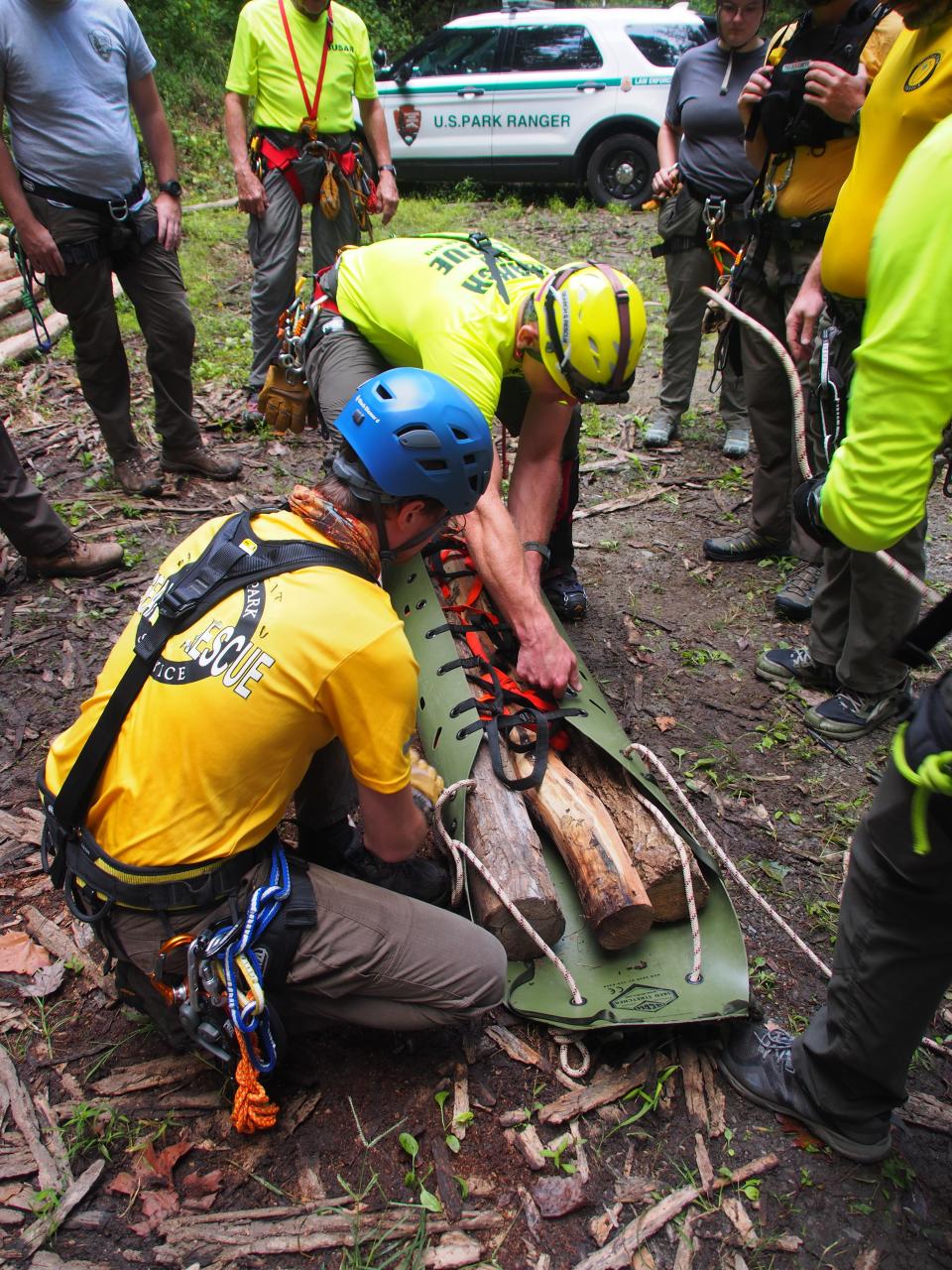 Tech-rescuers with their ersatz patient, three bundled locust logs simulating actual human weight.