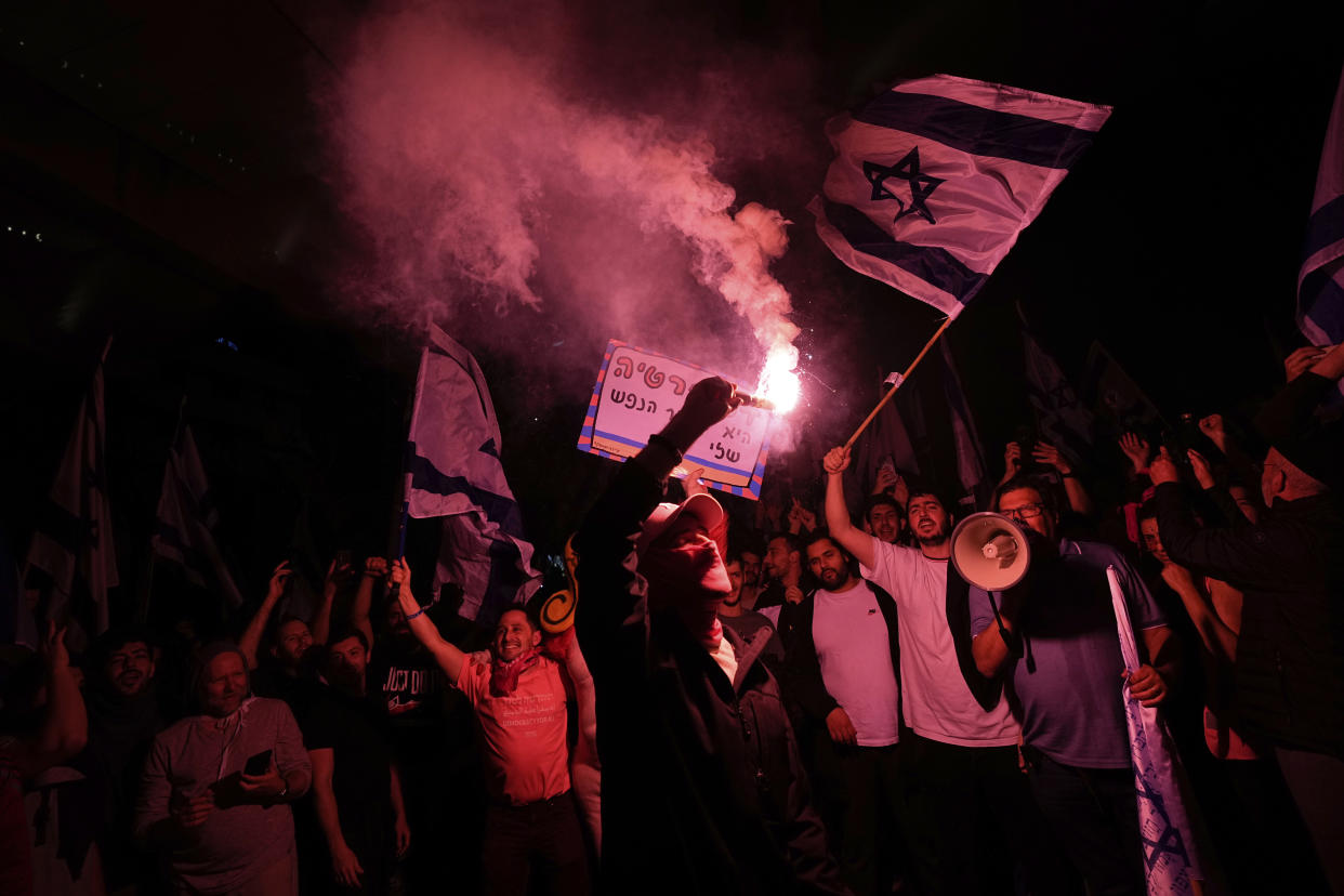 Israelis opposed to Prime Minister Benjamin Netanyahu's judicial overhaul plan block a highway during a protest after the Israeli leader fired his defense minister, in Tel Aviv, Israel, Monday, March 27, 2023. Defense Minister Yoav Gallant had called on Netanyahu to freeze the plan, citing deep divisions in the country and turmoil in the military. (AP Photo/Ohad Zwigenberg)