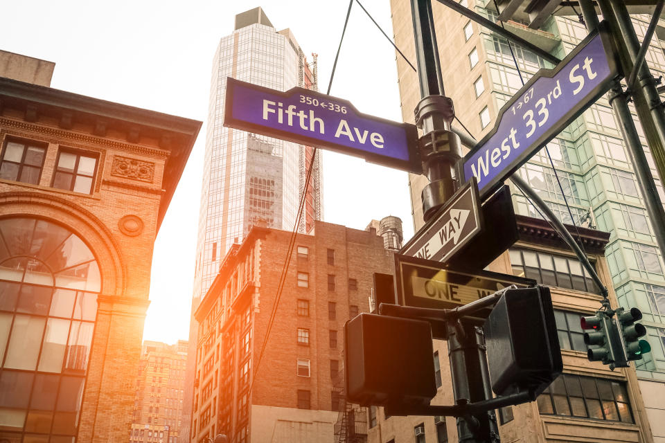 Street sign of Fifth Ave and West 33rd St at sunset in New York City - Urban concept and road direction in Manhattan downtown - American world famous capital destination on warm dramatic filtered look