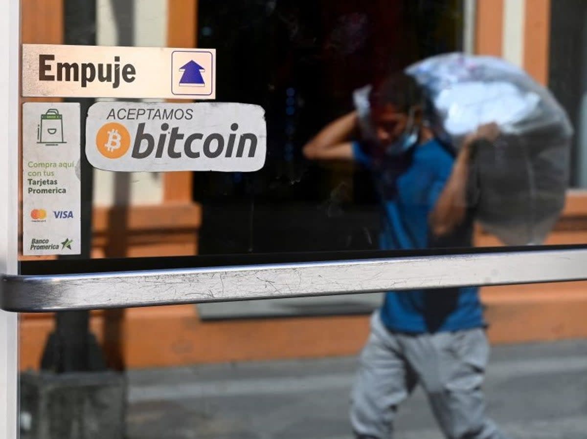 A man walks in front of a sign of a business where payments are accepted in bitcoin in San Salvador, on 17 November, 2022 (Getty Images)