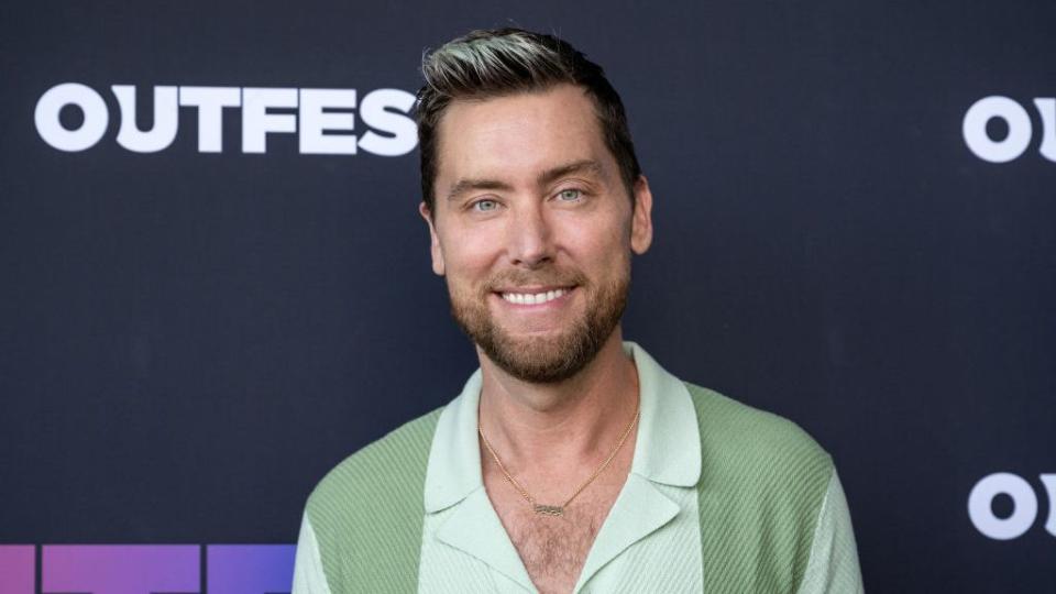 lance bass smiling for a photographer in front of a premiere event backdrop