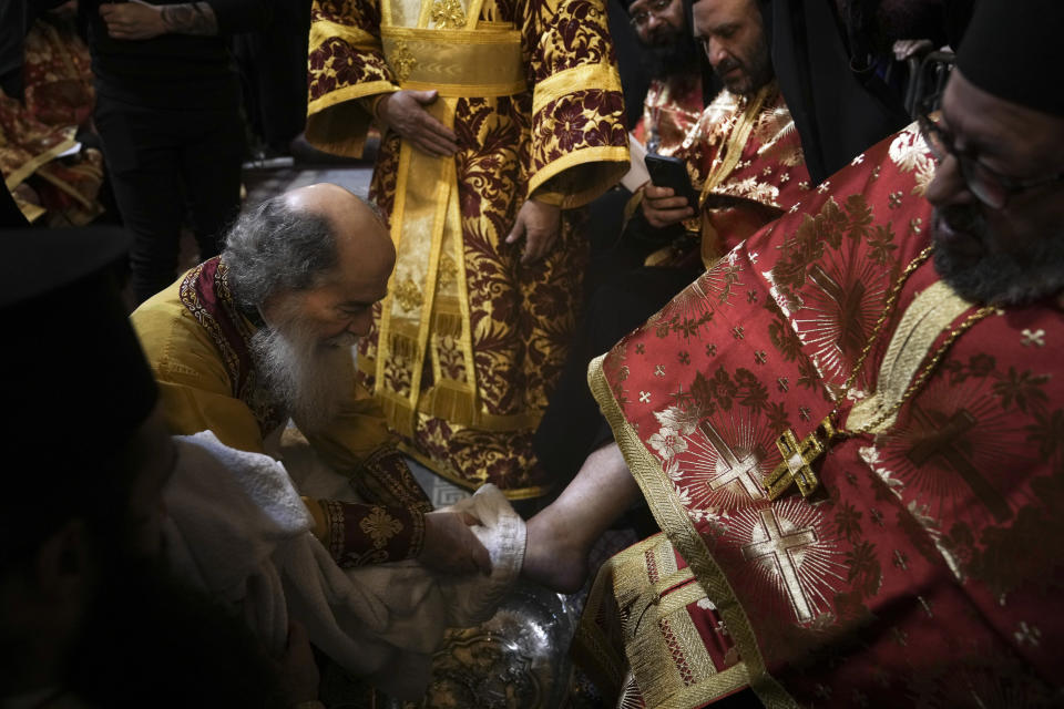 Patriarch Theophilos III, the Greek Orthodox Patriarch of Jerusalem, left, performs the Washing of the Feet ceremony during the Holy Week, at the Church of the Holy Sepulcher, where many Christians believe Jesus was crucified, buried and rose from the dead, in Jerusalem's Old City, Thursday, April 13, 2023. (AP Photo/Mahmoud Illean)