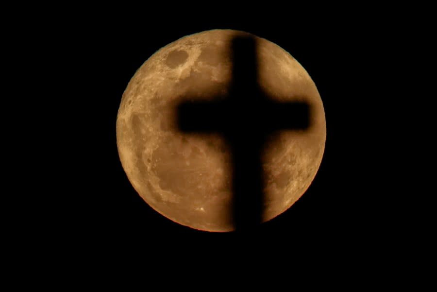 A supermoon rises over a headstone at a cemetery in Sydney, Australia, Thursday, Aug. 31, 2023. The cosmic curtain rose with the second full moon of the month, also known as a blue moon. A little bigger and brighter thanks to its slightly closer position to Earth. (AP Photo/Mark Baker)