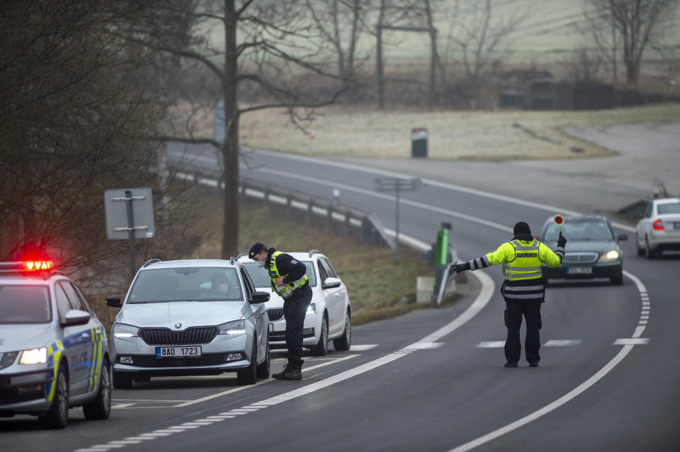 Police officers check cars on a road between the towns, Ceske Budejovice and Cesky Krumlov, near Kosov, Czech Republic, Monday, March 1, 2021. Limits for free movement of people are set in place in the Czech Republic. Travelling to other counties unless they go to work or have to take care about relatives is prohibited.(Vaclav Pancer/CTK via AP)