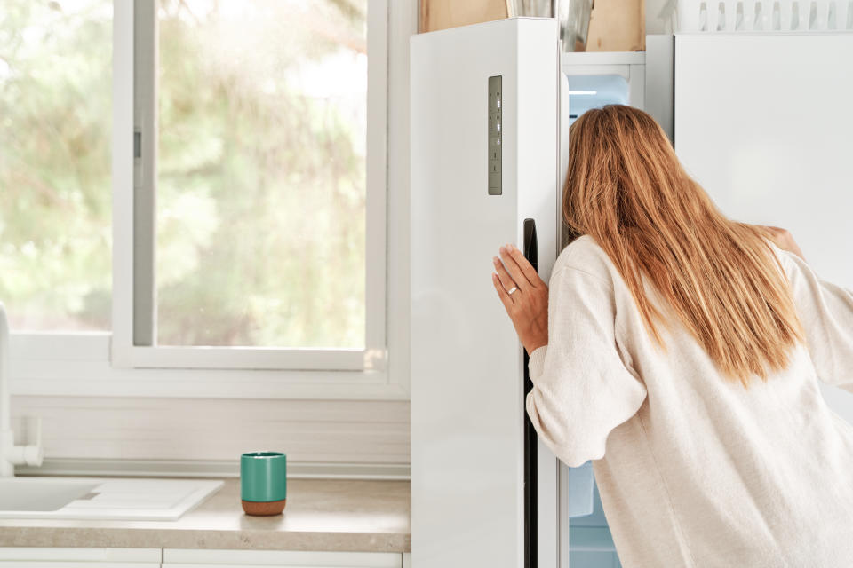 Young pretty woman in casual clothes looking inside her refrigerator in the kitchen.