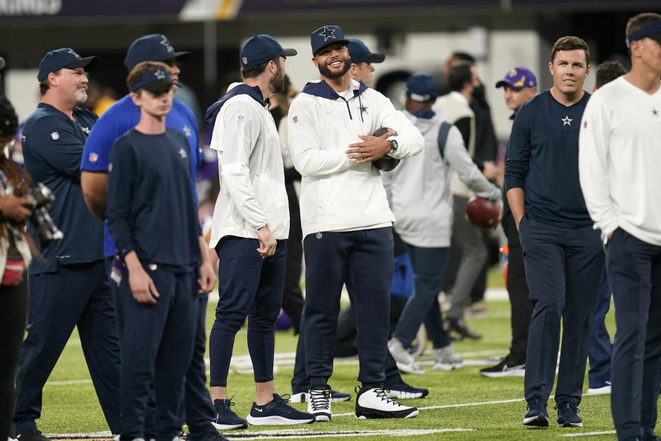 Injured Dallas Cowboys quarterback Dak Prescott, center, stands on the field before an NFL football game against the Minnesota Vikings, Sunday, Oct. 31, 2021, in Minneapolis. (AP Photo/Jim Mone)