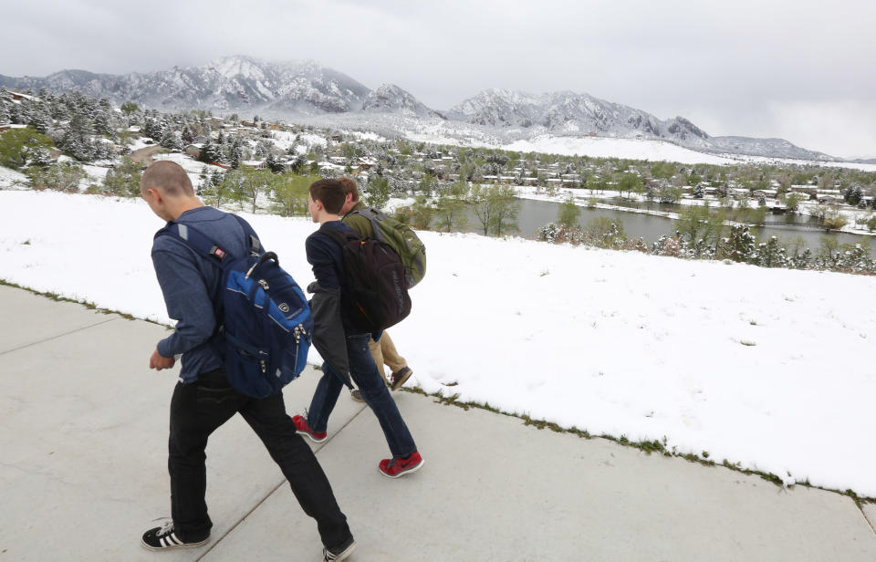 High school students walk past fresh snow from the fringe of a major spring snowstorm in the nearby mountains, in Boulder, Colo., on Monday, May 12, 2014. A spring storm has brought up to 3 feet of snow to the Rockies and severe thunderstorms and tornadoes to the Midwest. In Colorado, the snow that began falling on Mother's Day caused some power outages as it weighed down newly greening trees. (AP Photo/Brennan Linsley)