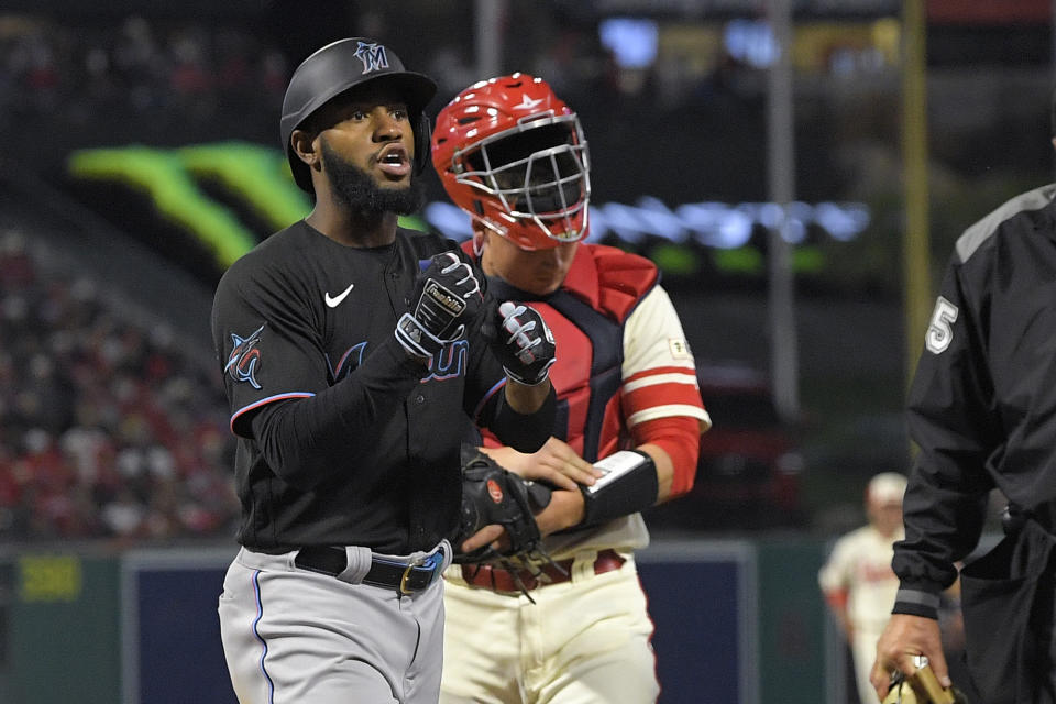 Miami Marlins' Bryan De La Cruz, left, gestures as he scores after hitting a two-run home run as Los Angeles Angels catcher Chad Wallach stands at the plate during the seventh inning of a baseball game Friday, May 26, 2023, in Anaheim, Calif. (AP Photo/Mark J. Terrill)