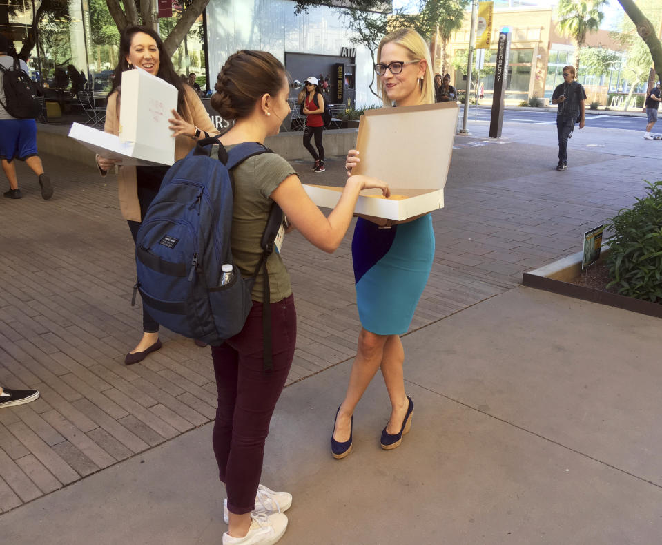 CORRECTS TO DOWNTOWN PHOENIX CAMPUS NOT TEMPE - Democratic Senate candidate Kyrsten Sinema hands out doughnuts to Arizona State University students on the campus in downtown Phoenix on Monday, Nov. 5, 2018. Sinema, a congresswoman who teaches at the school, closed out her campaign against Republican Rep. Martha McSally with a dash across the Phoenix metro area. (AP Photo/Nicolas Riccardi)