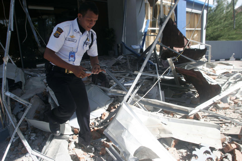 A security officer walks through debris from Wednesday's strong earthquake at an office building in Banda Aceh, Aceh province, Sumatra island, Indonesia, Thursday, April 12, 2012. Cries of panic and fervent prayers rang out Wednesday as Indonesians rushed toward high ground after two strong earthquakes raised fears of a killer tsunami. (AP Photo/Heri Juanda)