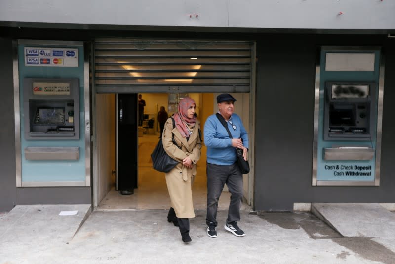 People walk past damaged ATM machines as they leave the Credit Libanais bank in Beirut