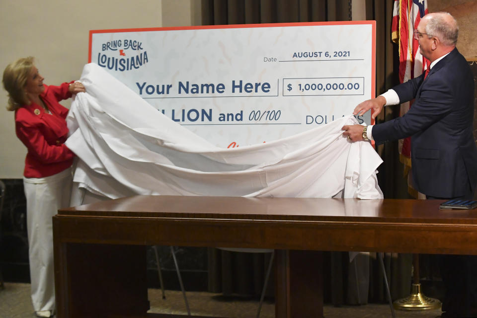 FILE - In this Thursday, June 17, 2021 file photo, first lady Donna Edwards, left, and Gov. John Bel Edwards, right, unveil a giant check during a news conference at the Louisiana State Capitol in Baton Rouge, La., to announce that Louisiana will participate in a lottery, giving cash prizes and scholarships to residents who have been vaccinated against the coronavirus. (Hilary Scheinuk/The Advocate via AP)